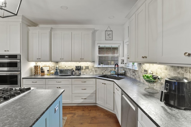 kitchen featuring appliances with stainless steel finishes, sink, white cabinets, and backsplash