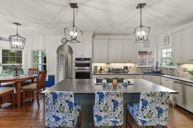 kitchen with appliances with stainless steel finishes, decorative light fixtures, sink, and a kitchen island