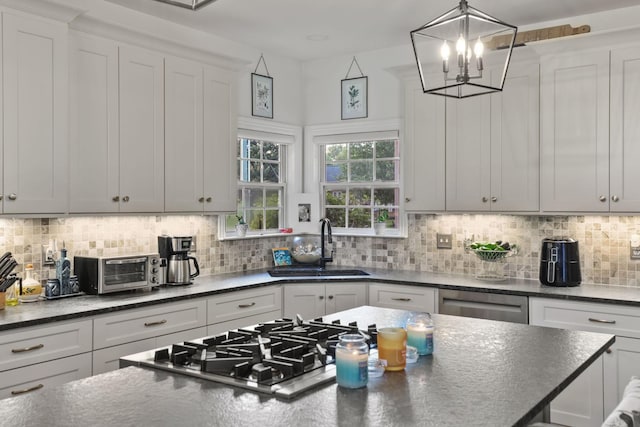 kitchen featuring white cabinetry, decorative backsplash, sink, and hanging light fixtures