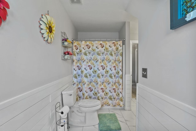 bathroom with a shower with curtain, tile patterned floors, and toilet