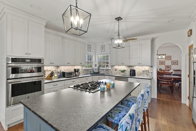 kitchen featuring pendant lighting, stainless steel appliances, a center island, and white cabinets