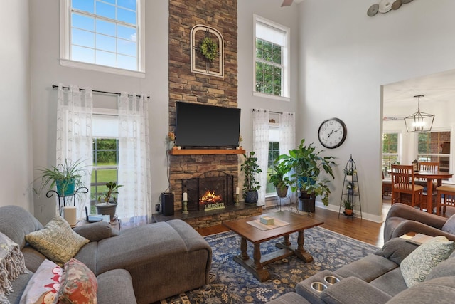 living room featuring a fireplace, a towering ceiling, wood-type flooring, and a chandelier