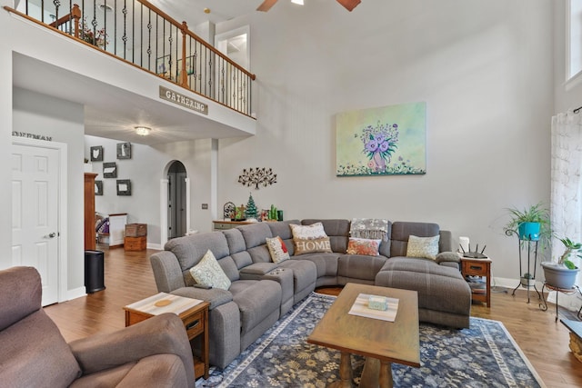 living room with a high ceiling, hardwood / wood-style floors, and ceiling fan