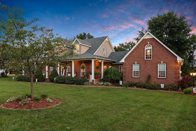 cape cod house with a porch and a yard