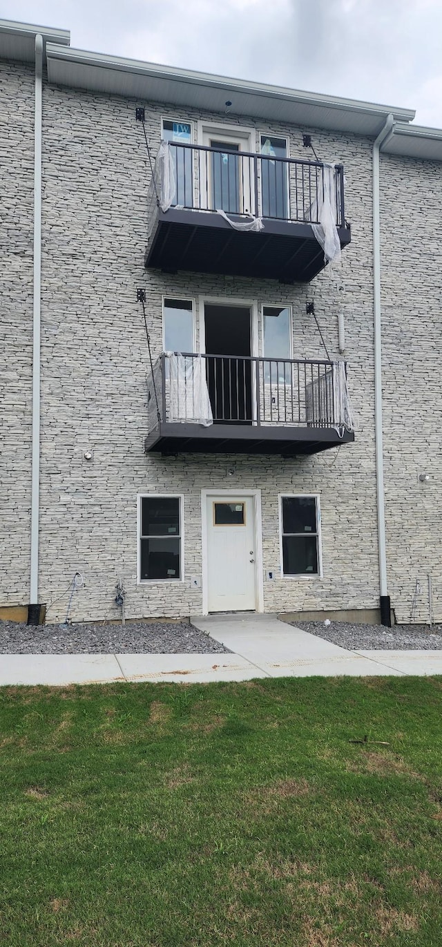 back of house featuring a yard and a balcony