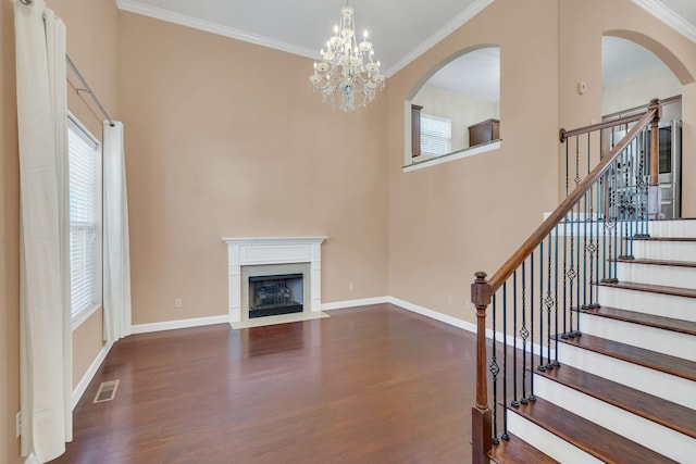 unfurnished living room featuring a notable chandelier, crown molding, and dark wood-type flooring