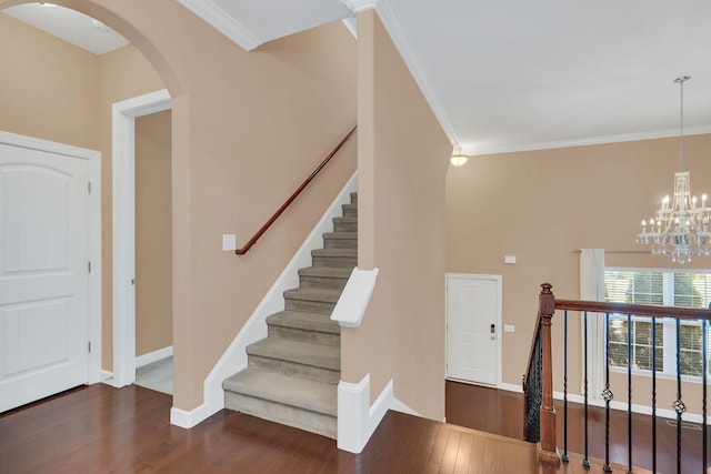 entrance foyer featuring crown molding, dark wood-type flooring, and a chandelier