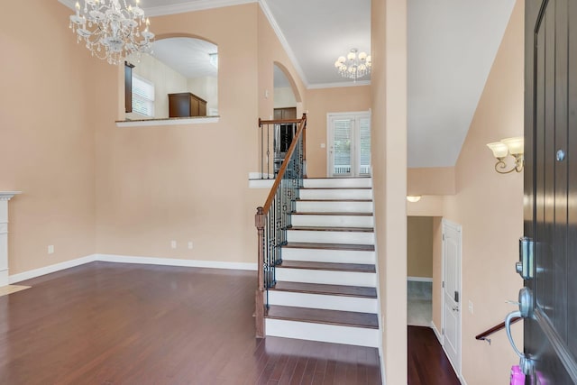 stairs with ornamental molding, wood-type flooring, and a notable chandelier