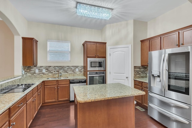 kitchen featuring dark wood-type flooring, sink, appliances with stainless steel finishes, a kitchen island, and backsplash