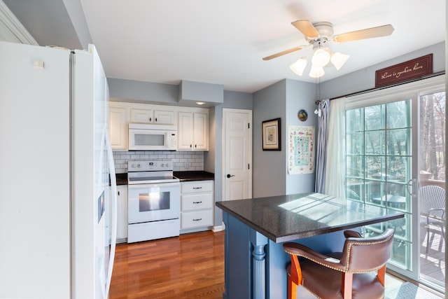 kitchen featuring white appliances, white cabinetry, decorative backsplash, dark countertops, and dark wood finished floors