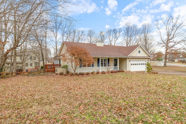 ranch-style home featuring driveway, a chimney, a porch, an attached garage, and a front lawn