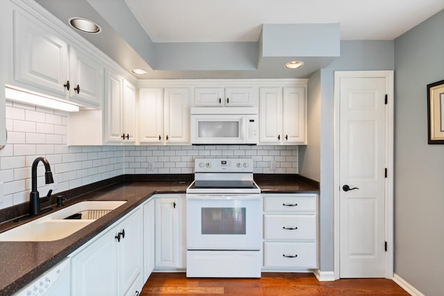 kitchen featuring sink, white appliances, hardwood / wood-style flooring, white cabinetry, and backsplash