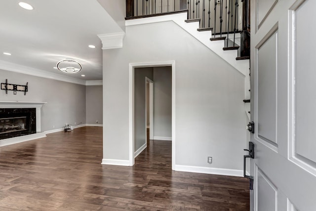 entrance foyer featuring ornate columns, ornamental molding, dark hardwood / wood-style floors, and a fireplace