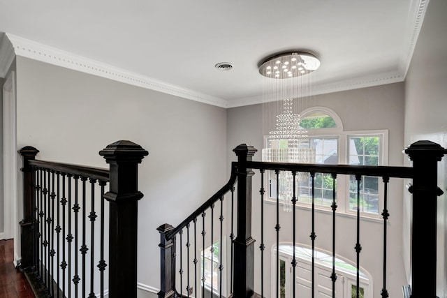 staircase with an inviting chandelier, ornamental molding, and wood-type flooring