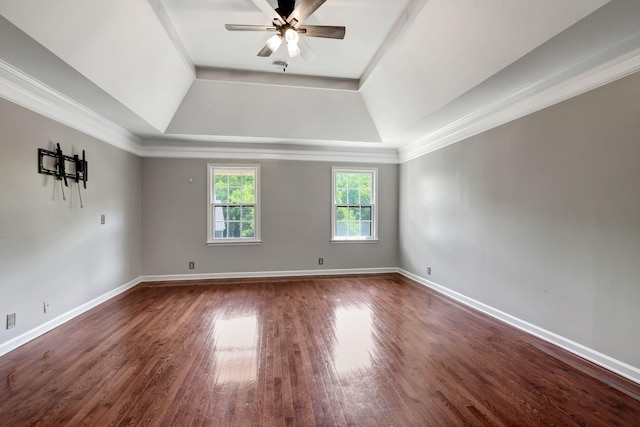 empty room with dark hardwood / wood-style flooring, a tray ceiling, ornamental molding, and ceiling fan