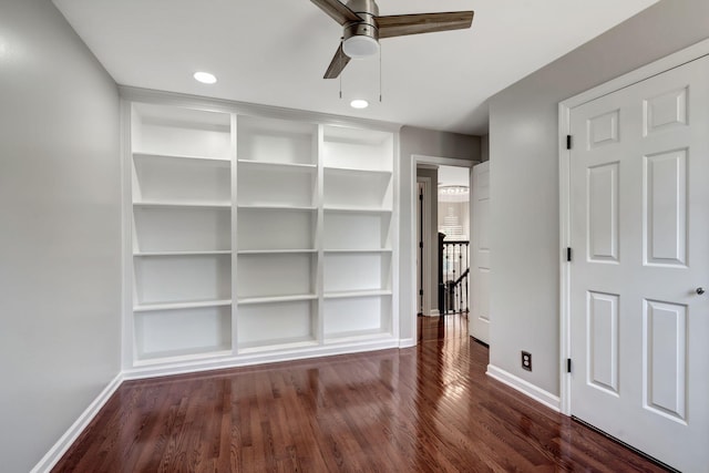 spare room featuring dark hardwood / wood-style flooring, built in features, and ceiling fan