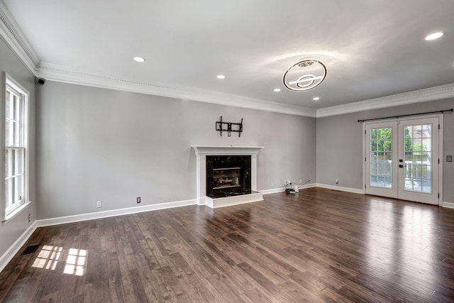 unfurnished living room with crown molding, a fireplace, dark hardwood / wood-style floors, and french doors