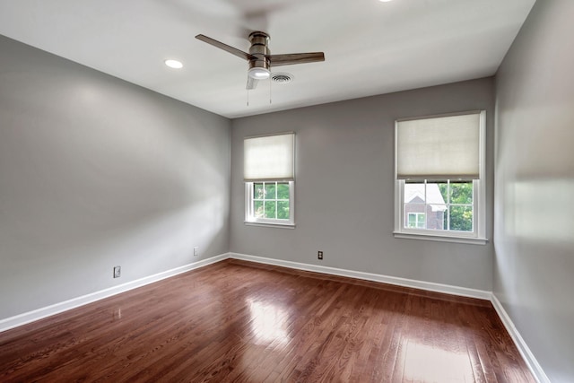 empty room with dark hardwood / wood-style flooring, ceiling fan, and a healthy amount of sunlight