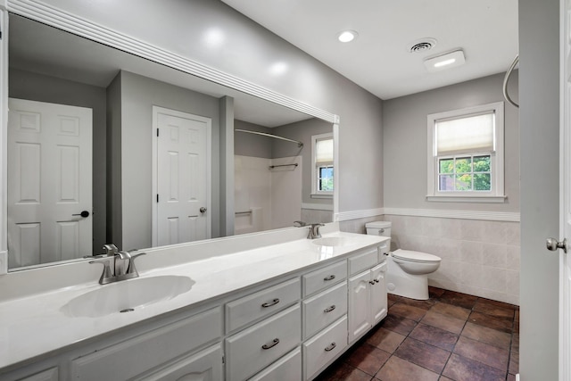 bathroom featuring vanity, tile walls, and toilet