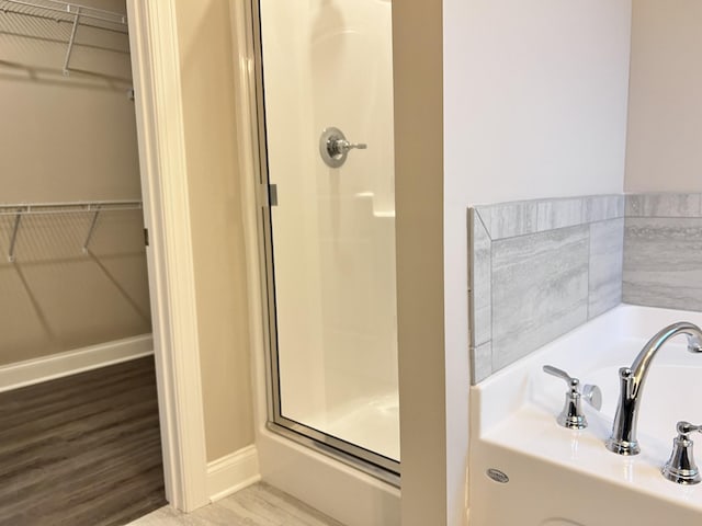 bathroom with independent shower and bath, sink, and hardwood / wood-style floors