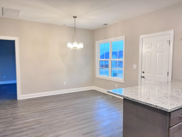 kitchen featuring dark hardwood / wood-style floors, decorative light fixtures, a chandelier, light stone counters, and dark brown cabinets