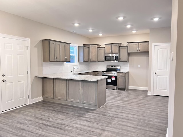 kitchen featuring appliances with stainless steel finishes, sink, hardwood / wood-style floors, and kitchen peninsula