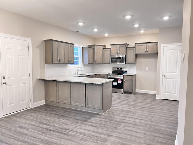 kitchen with hardwood / wood-style flooring, stainless steel appliances, kitchen peninsula, and sink