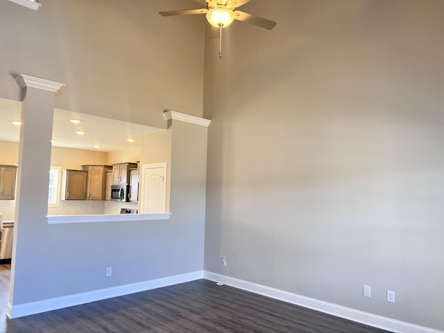 unfurnished living room featuring ceiling fan, dark hardwood / wood-style flooring, and decorative columns