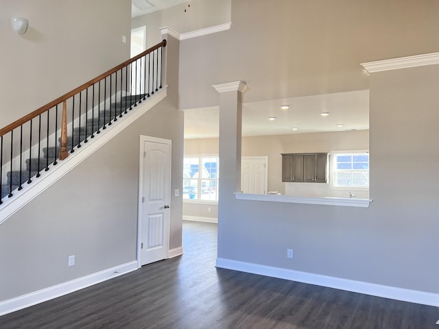 unfurnished living room featuring ornate columns and dark hardwood / wood-style floors