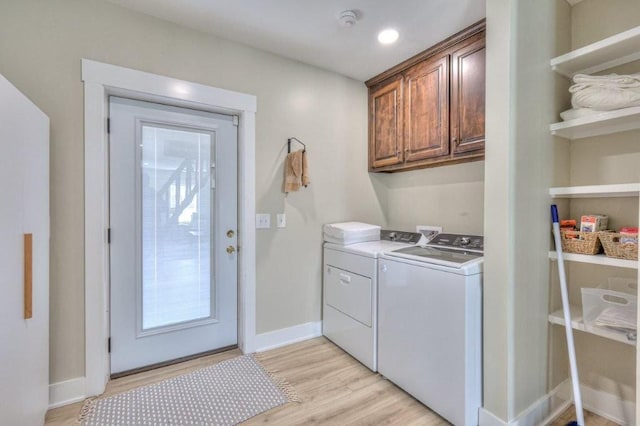 laundry area with cabinets, washer and clothes dryer, and light hardwood / wood-style floors