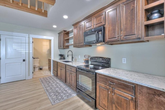 kitchen with light stone counters, sink, black appliances, and light wood-type flooring