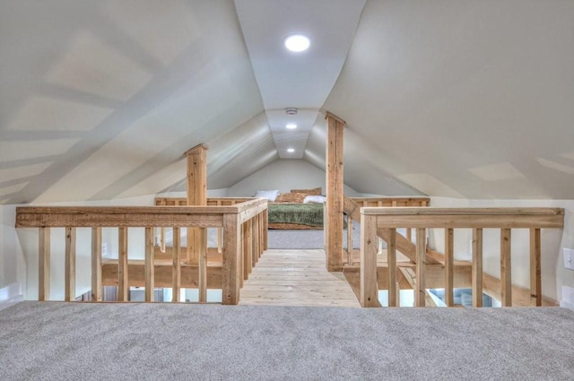 additional living space featuring vaulted ceiling and light colored carpet