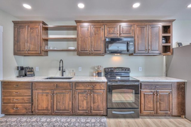 kitchen with light stone countertops, sink, light hardwood / wood-style floors, and black appliances