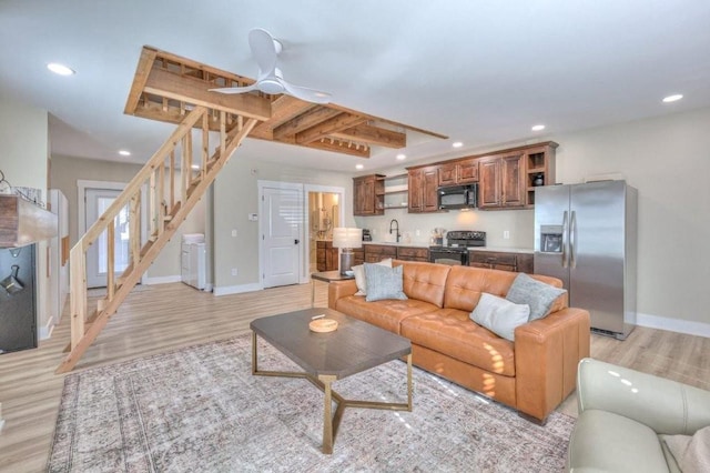 living room featuring sink, beam ceiling, light hardwood / wood-style flooring, and ceiling fan