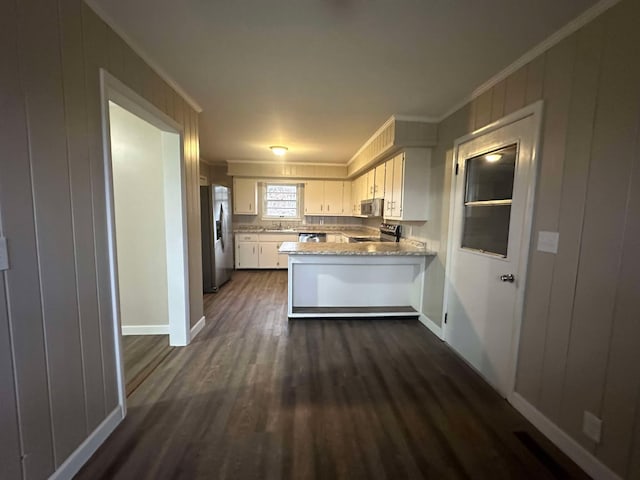 kitchen featuring crown molding, white cabinetry, stainless steel appliances, dark hardwood / wood-style floors, and kitchen peninsula