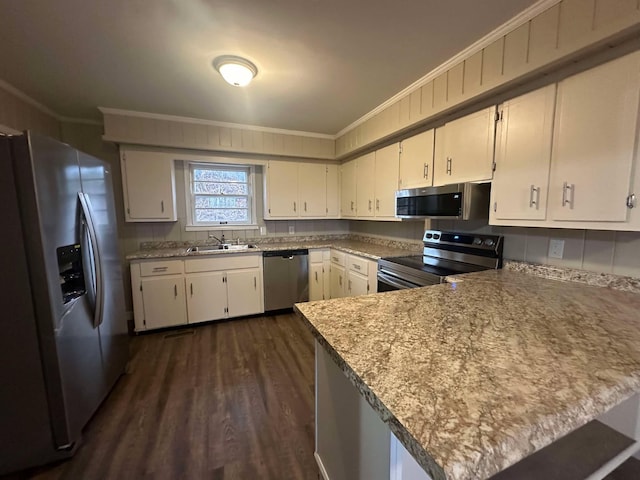 kitchen with crown molding, stainless steel appliances, kitchen peninsula, and white cabinets