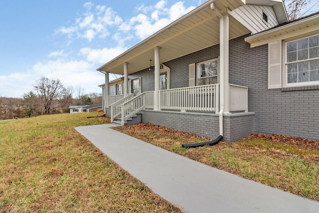 doorway to property featuring brick siding, a porch, and a yard