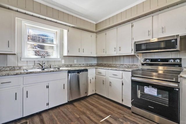 kitchen featuring dark wood-style floors, appliances with stainless steel finishes, ornamental molding, white cabinets, and a sink