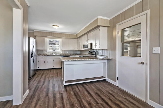 kitchen featuring appliances with stainless steel finishes, white cabinets, a sink, and a peninsula