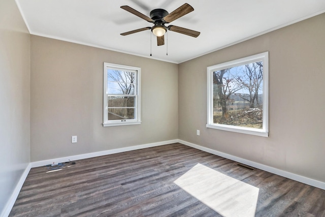 empty room featuring dark wood-style flooring, visible vents, and baseboards