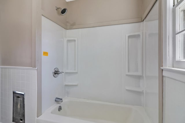 bathroom with a wainscoted wall, tub / shower combination, tile walls, and heating unit