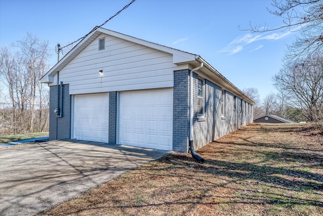 view of side of home featuring brick siding and a detached garage