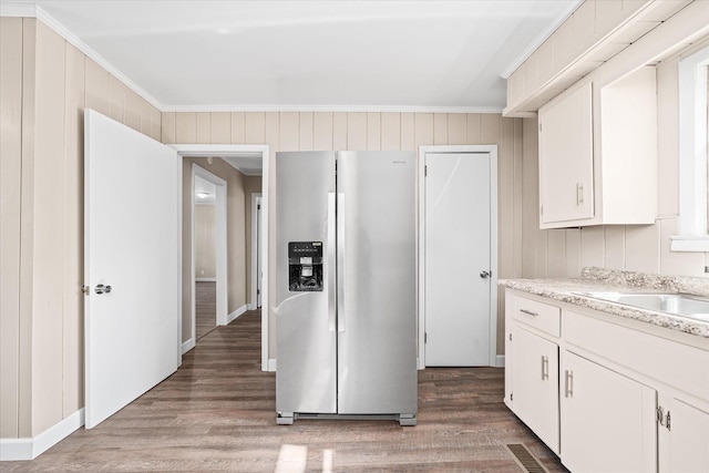 kitchen featuring white cabinets, crown molding, stainless steel refrigerator with ice dispenser, and wood finished floors