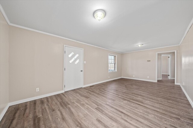 interior space featuring ornamental molding, wood finished floors, and baseboards