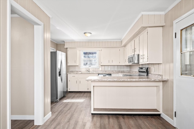 kitchen with white cabinets, a peninsula, stainless steel appliances, and a sink