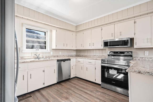 kitchen featuring appliances with stainless steel finishes, light countertops, a sink, and white cabinetry