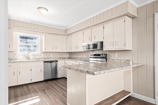 kitchen featuring appliances with stainless steel finishes, white cabinets, ornamental molding, and a peninsula