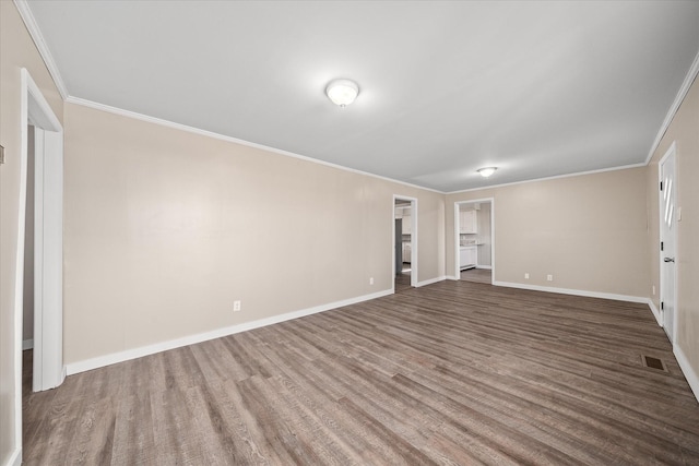 empty room featuring baseboards, wood finished floors, visible vents, and crown molding