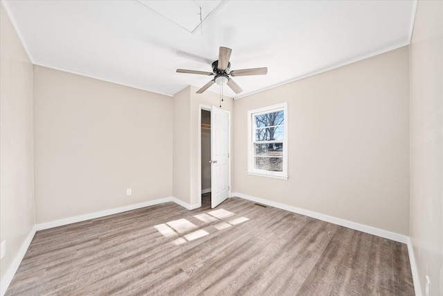 unfurnished bedroom with attic access, baseboards, visible vents, wood finished floors, and a closet