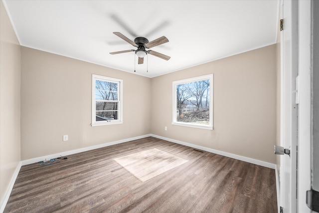 unfurnished room with dark wood-style floors, visible vents, a wealth of natural light, and baseboards